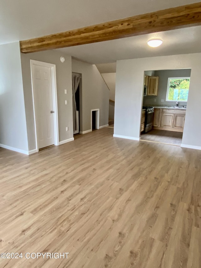 unfurnished living room with beam ceiling and light hardwood / wood-style flooring