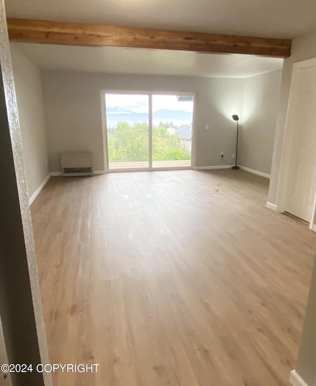 empty room with beam ceiling and light hardwood / wood-style floors