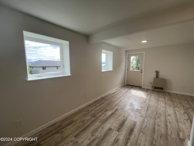 unfurnished room featuring beam ceiling and light hardwood / wood-style flooring