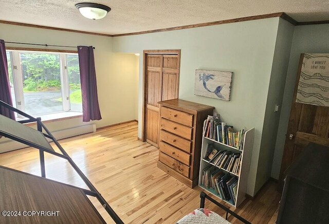 bedroom with light hardwood / wood-style floors, crown molding, and a textured ceiling