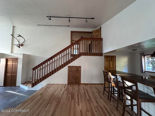 staircase with a towering ceiling, hardwood / wood-style floors, and track lighting