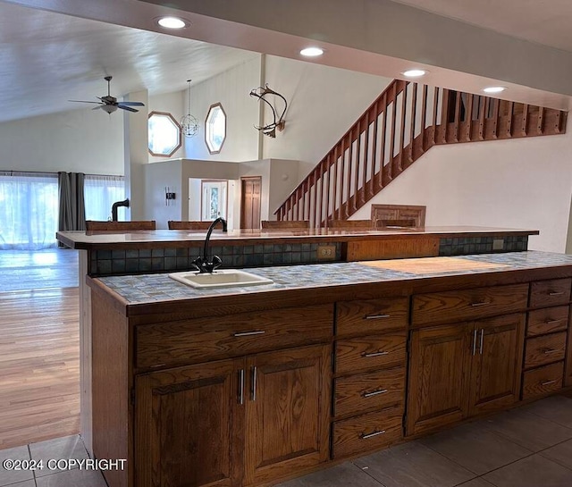 kitchen with lofted ceiling, hardwood / wood-style flooring, sink, decorative light fixtures, and ceiling fan