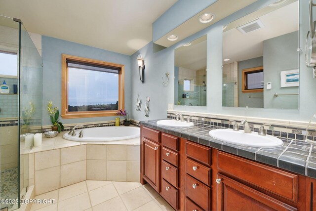 bathroom featuring plus walk in shower, backsplash, tile patterned flooring, and dual bowl vanity