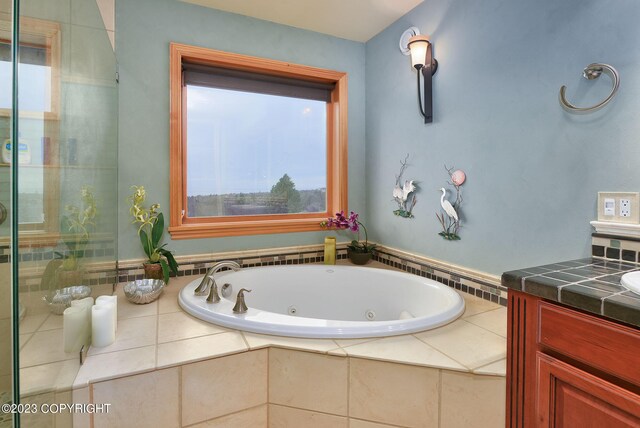 bathroom featuring a relaxing tiled tub and vanity