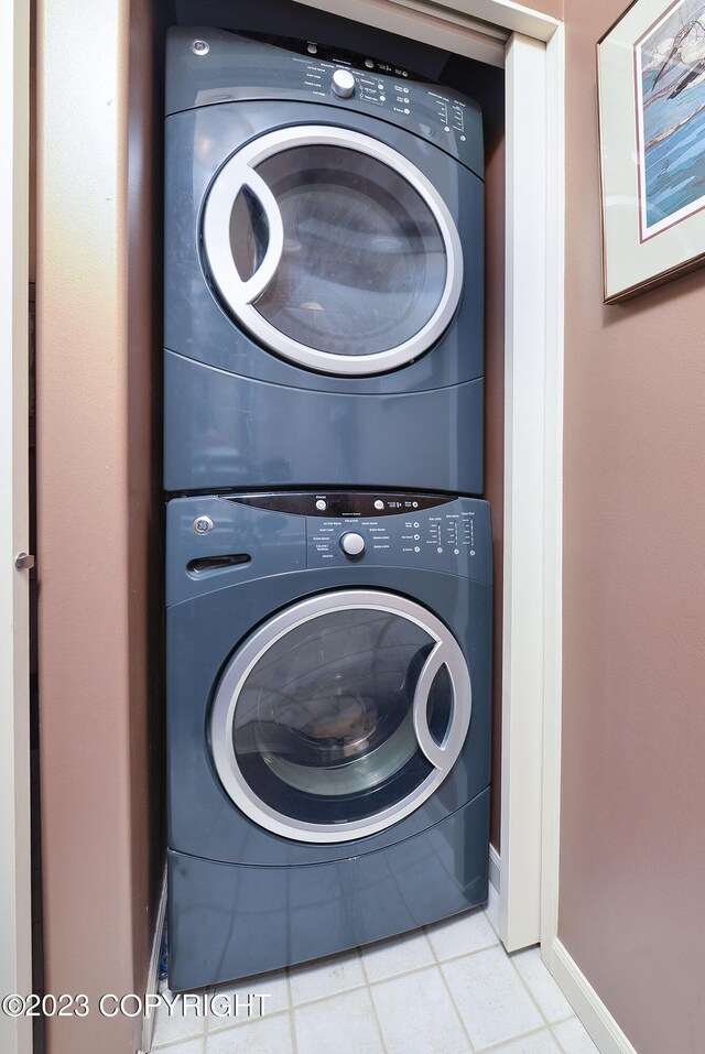 laundry room featuring light tile patterned flooring and stacked washing maching and dryer