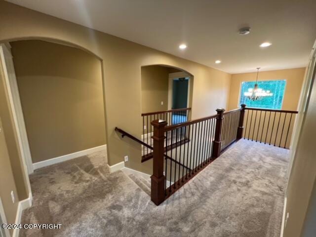 hallway featuring an inviting chandelier and carpet flooring