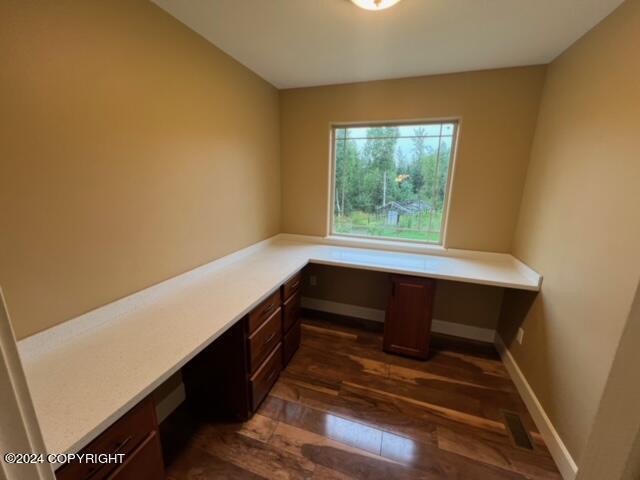 unfurnished office featuring dark wood-type flooring and built in desk