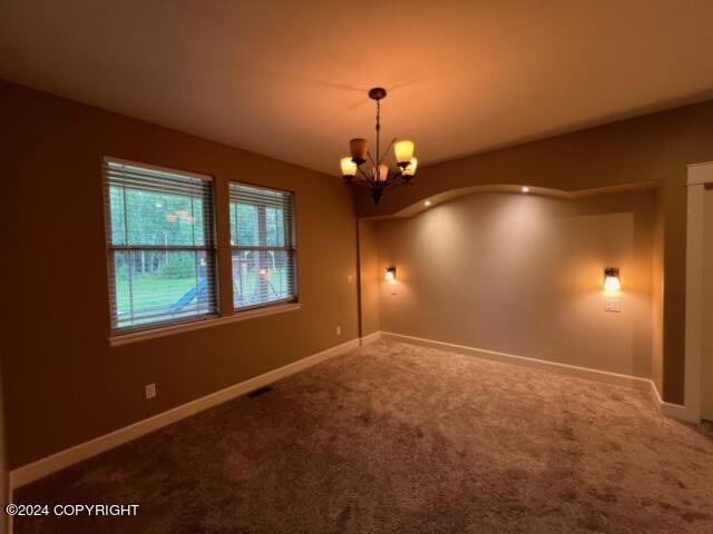 carpeted spare room featuring a notable chandelier