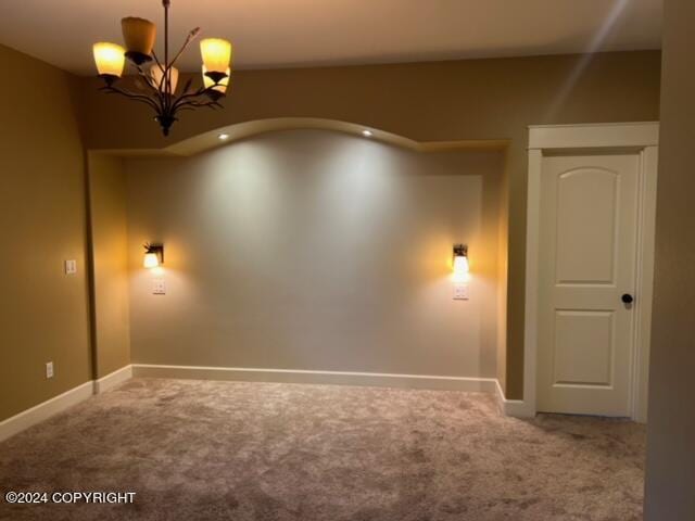 carpeted spare room with an inviting chandelier