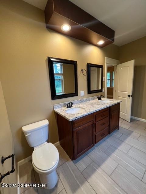 bathroom featuring tile patterned flooring, toilet, and double sink vanity