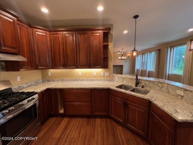 kitchen with gas range, decorative light fixtures, sink, kitchen peninsula, and dark wood-type flooring