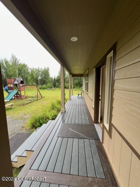 wooden terrace with a playground and a yard