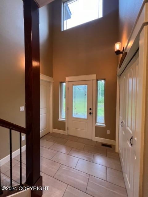 tiled foyer entrance with a towering ceiling and plenty of natural light