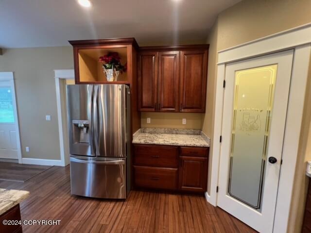 kitchen with dark wood-type flooring, light stone countertops, and stainless steel refrigerator with ice dispenser