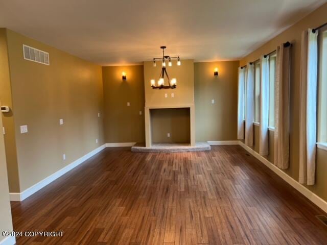 unfurnished living room with dark hardwood / wood-style floors and a notable chandelier