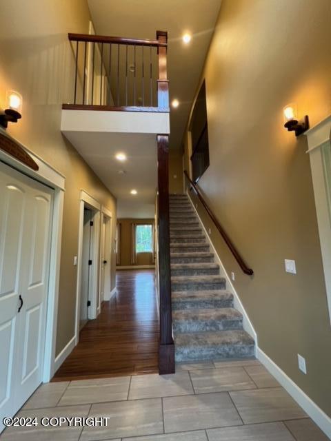 stairway with wood-type flooring and a high ceiling