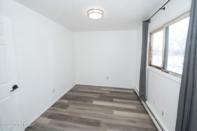 empty room with a baseboard radiator, a textured ceiling, and dark hardwood / wood-style flooring