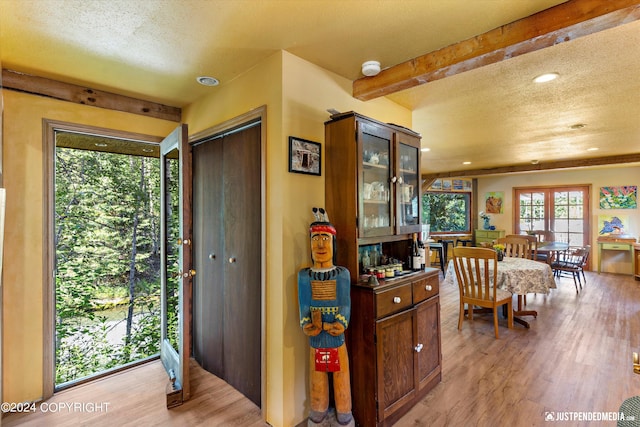 interior space with light hardwood / wood-style floors, beamed ceiling, and a textured ceiling