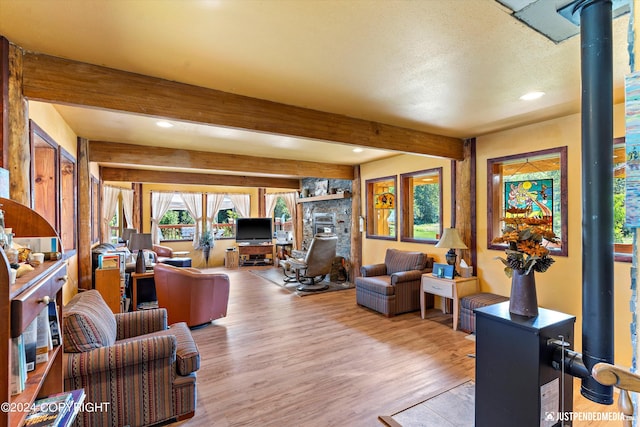 living room featuring light hardwood / wood-style flooring, a wood stove, and beam ceiling