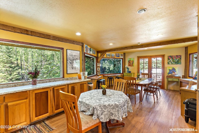 dining space with light wood-type flooring, a textured ceiling, and french doors