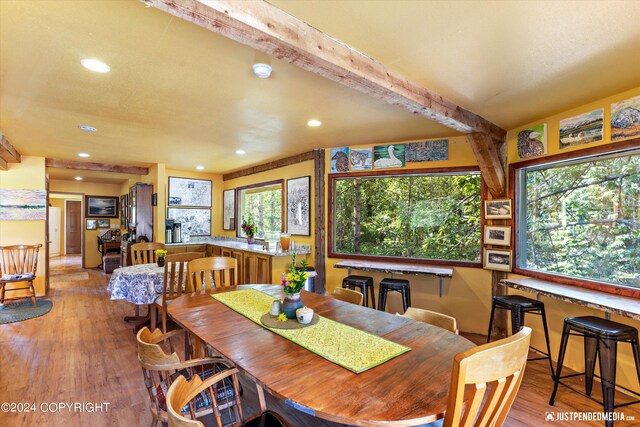 dining space featuring light wood-type flooring, beamed ceiling, and plenty of natural light