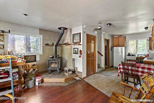 interior space with wood-type flooring, tile walls, plenty of natural light, and a wood stove