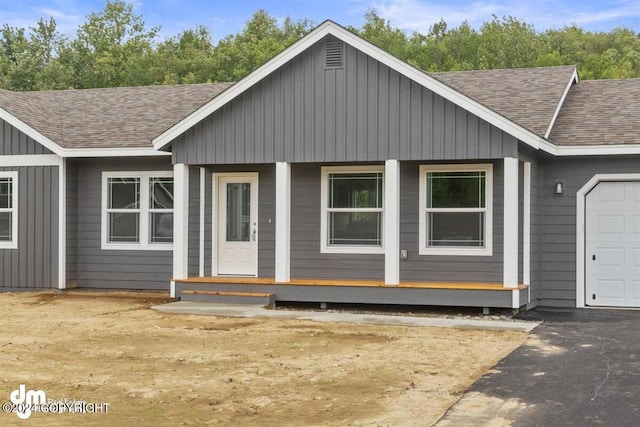 view of front of house with a shingled roof, board and batten siding, and an attached garage