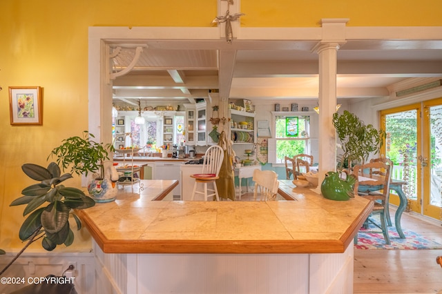 kitchen featuring light wood-type flooring, ornate columns, beam ceiling, white dishwasher, and coffered ceiling