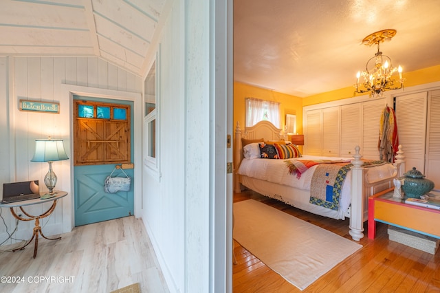 bedroom featuring light hardwood / wood-style flooring, a chandelier, and lofted ceiling