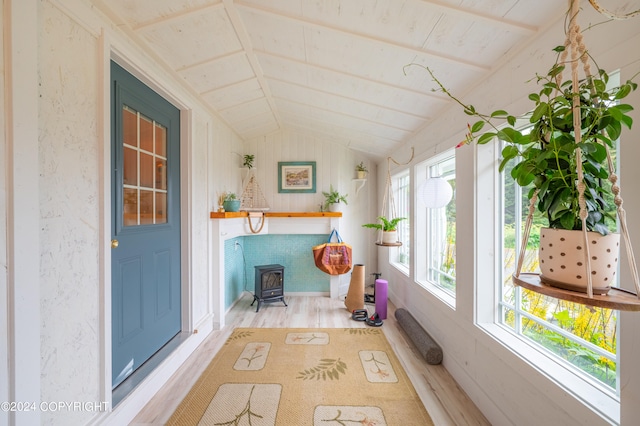 unfurnished sunroom featuring a wood stove and lofted ceiling