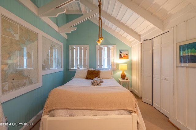 bedroom with lofted ceiling with beams, light carpet, and a closet