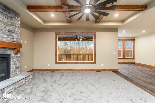 unfurnished living room featuring a stone fireplace, ceiling fan, and carpet floors