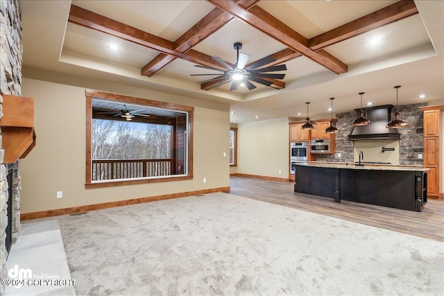 unfurnished living room featuring ceiling fan, a fireplace, coffered ceiling, beamed ceiling, and light wood-type flooring