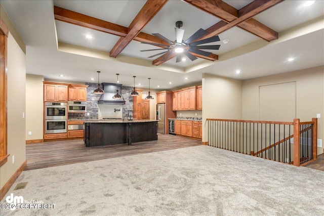 kitchen featuring custom exhaust hood, a kitchen island with sink, coffered ceiling, stainless steel appliances, and wood-type flooring