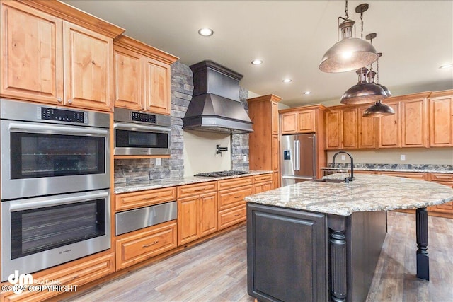 kitchen featuring appliances with stainless steel finishes, light hardwood / wood-style floors, premium range hood, and light stone countertops