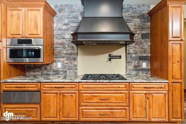 kitchen with custom exhaust hood, stainless steel appliances, and dark stone countertops