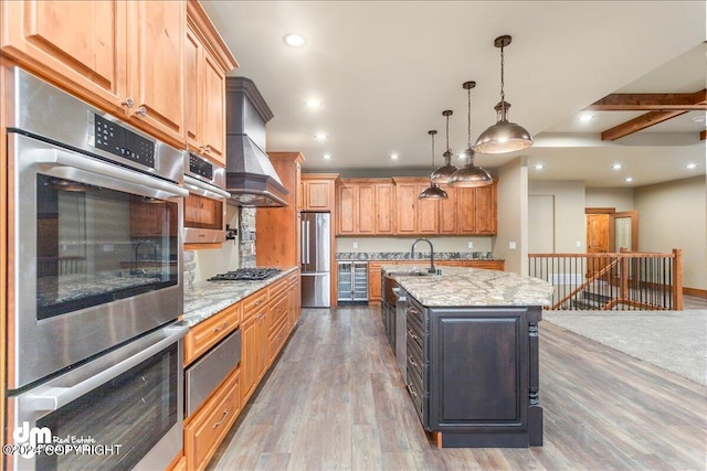 kitchen featuring stainless steel appliances, a kitchen island with sink, light stone countertops, dark wood-type flooring, and custom range hood