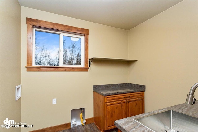 laundry area with dark wood-type flooring, cabinets, and sink