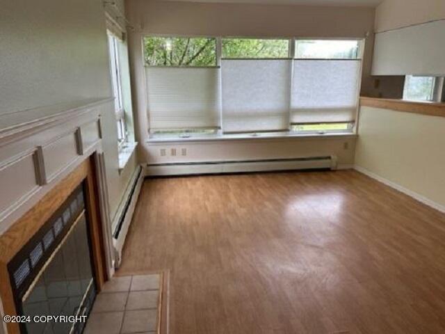 unfurnished sunroom featuring a baseboard radiator, a healthy amount of sunlight, and baseboard heating