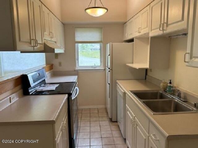 kitchen featuring dishwasher, light countertops, a sink, and range