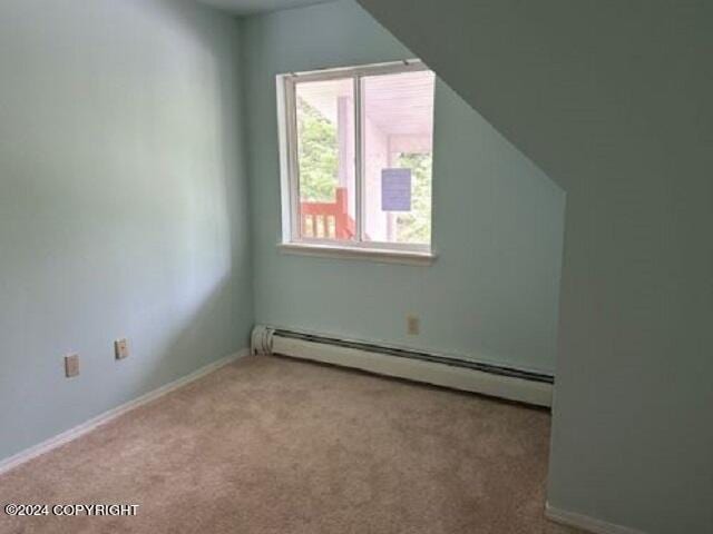 bonus room with a baseboard heating unit and carpet flooring