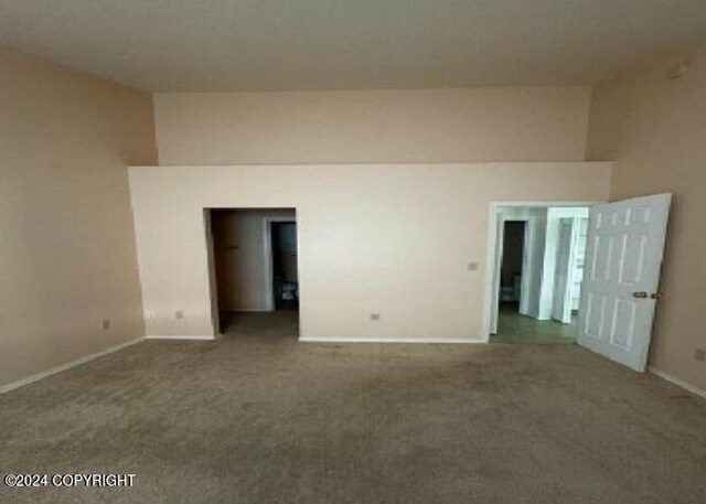 carpeted spare room with a towering ceiling and baseboards