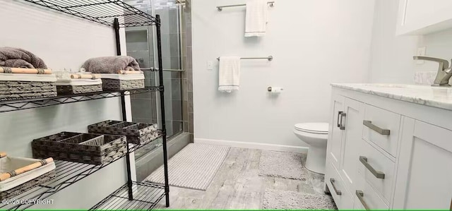 bathroom with toilet, vanity, walk in shower, and wood-type flooring