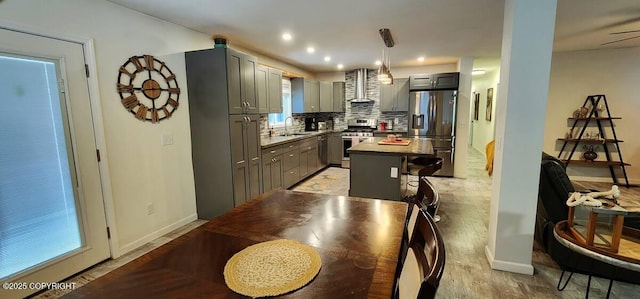 kitchen with appliances with stainless steel finishes, a center island, wall chimney range hood, gray cabinets, and decorative backsplash