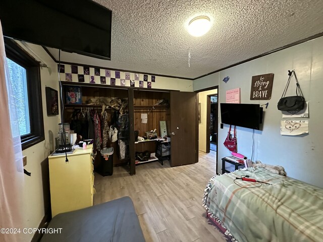 bedroom featuring multiple windows, a closet, a textured ceiling, and light hardwood / wood-style floors