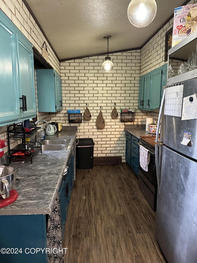 kitchen with vaulted ceiling, black refrigerator, range with electric cooktop, and brick wall