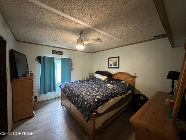 bedroom with ceiling fan, wood-type flooring, and a textured ceiling