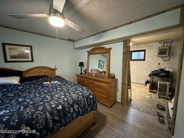 bedroom featuring a textured ceiling, ceiling fan, ornamental molding, and wood-type flooring