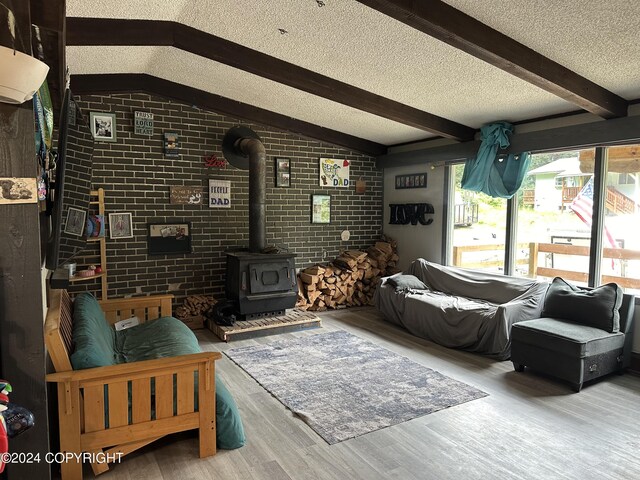 living room featuring a textured ceiling, brick wall, hardwood / wood-style flooring, and a wood stove