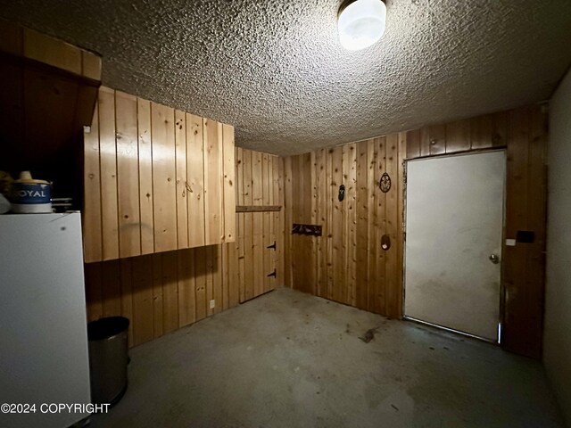 empty room with wooden walls, a textured ceiling, and carpet flooring